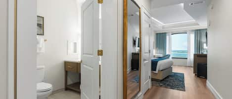 A modern hotel room with a large bed, a desk, and a view of the ocean.