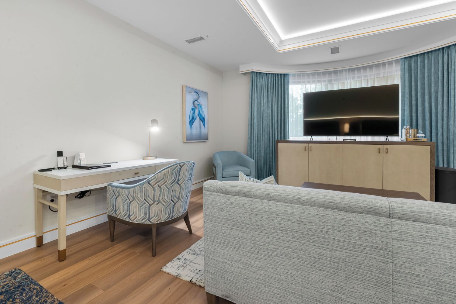 Una habitación moderna y bien iluminada con escritorio, silla, sofá y televisor.