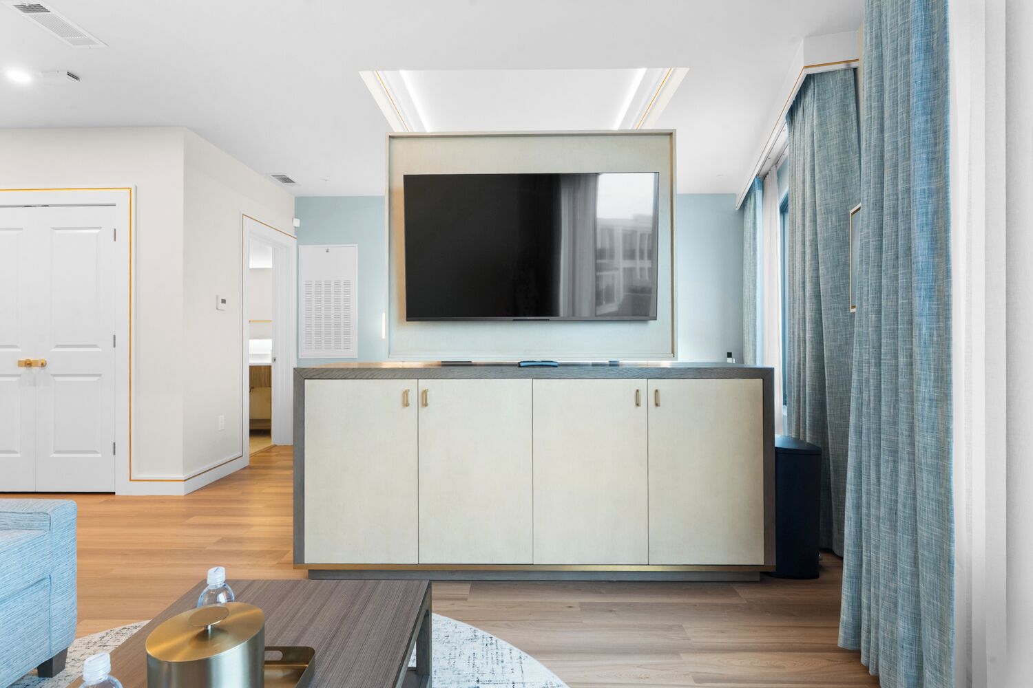 Una cocina moderna con una isla central grande, un televisor de pantalla plana sobre la isla y un comedor con una mesa y sillas.