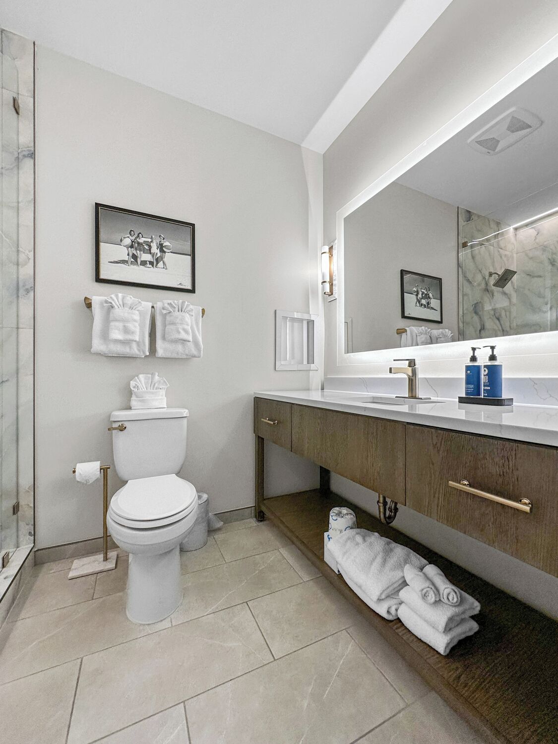 A modern bathroom with a toilet, sink, and shower. There are towels and toiletries on the counter.