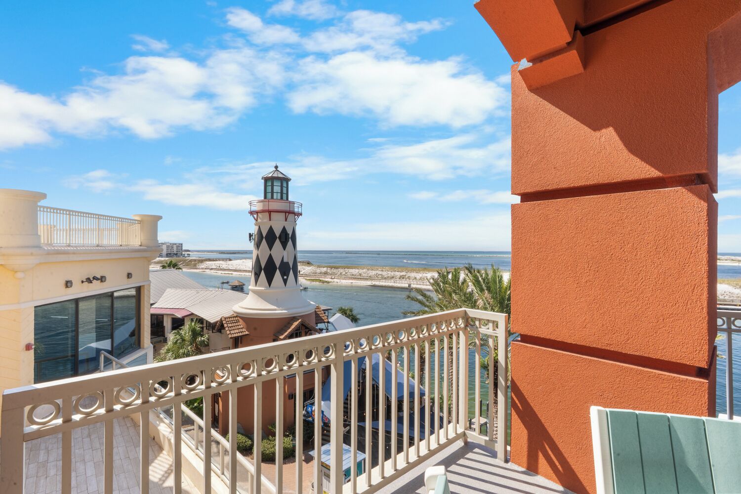 A balcony with a view of a lighthouse, beach, and ocean.