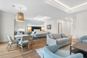 Una habitación de hotel moderna con una cama, zona de estar y una mesa de comedor.
