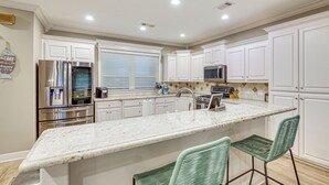 A modern kitchen with white cabinets, stainless steel appliances, a granite countertop, and two green bar stools. - Tranquil Views: Riverfront Retreat in Hot Springs! (Hot Springs)