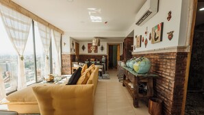 Una sala moderna con un sofá amarillo, un comedor con una pared de ladrillo decorativa y obras de arte en las paredes.