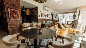 Una sala de estar acogedora con una mesa redonda, sillas cómodas, un sofá y una chimenea.