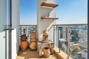Un balcón con jarrones grandes y una pequeña mesa, con vistas a una ciudad.
