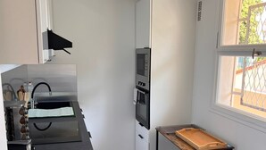 Eine kleine Küche mit Mikrowelle, Backofen und einem Tisch.