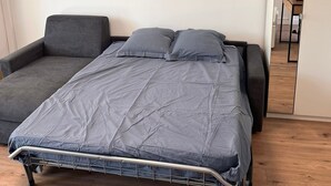 Ein Schlafzimmer mit einem Bett, einer Couch, einem Kleiderschrank und einem Spiegel.
