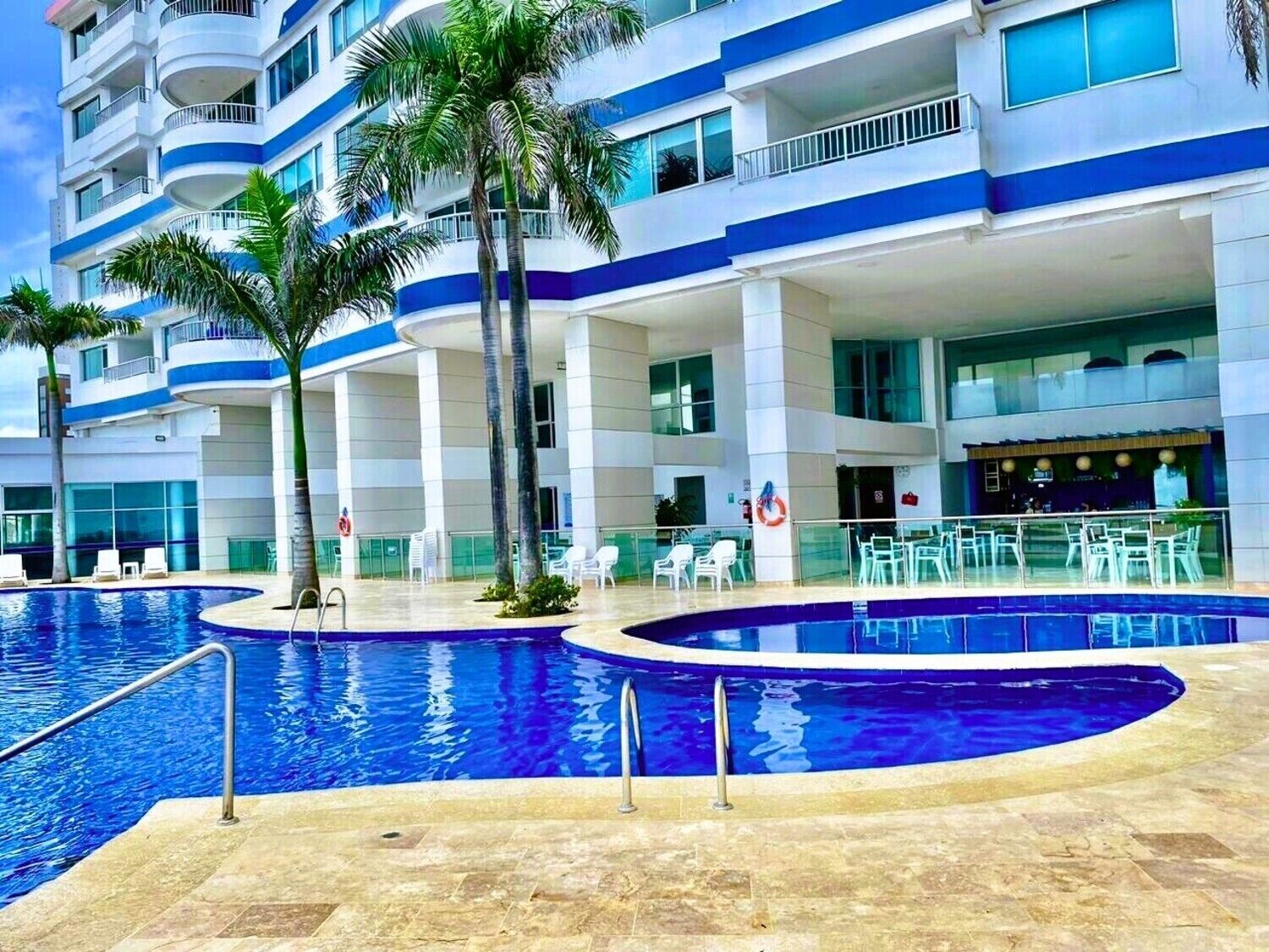 Um hotel com uma piscina grande ao ar livre, várias varandas e áreas de estar externas.