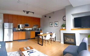 Ein modernes Wohnzimmer mit Essbereich, Küche und Kamin.
