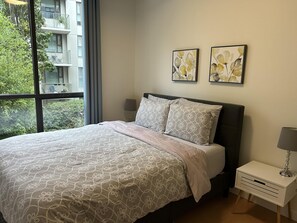 Ein Schlafzimmer mit einem Bett, einem Nachttisch und zwei an der Wand befestigten Blumenbildern.