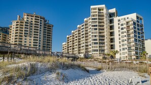Een hotel aan het strand met meerdere hoge gebouwen, een zandstrand en een houten looppad.