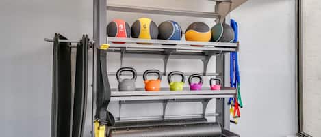 A wall-mounted rack with various exercise equipment, including kettlebells and resistance bands.