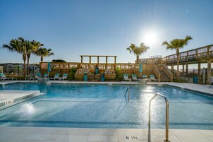 Una piscina al aire libre, sombrillas, sillones reclinables de piscina