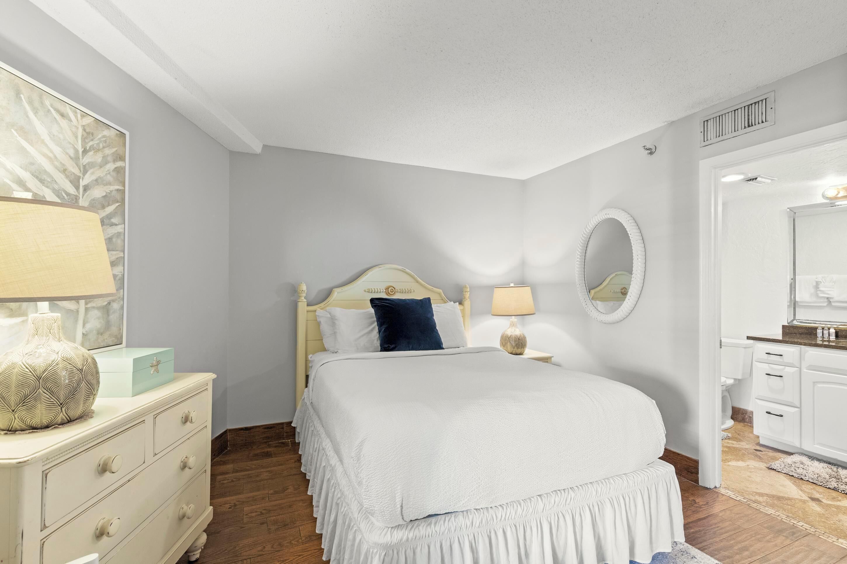 A bedroom with a bed, dresser, nightstand, and a mirror.