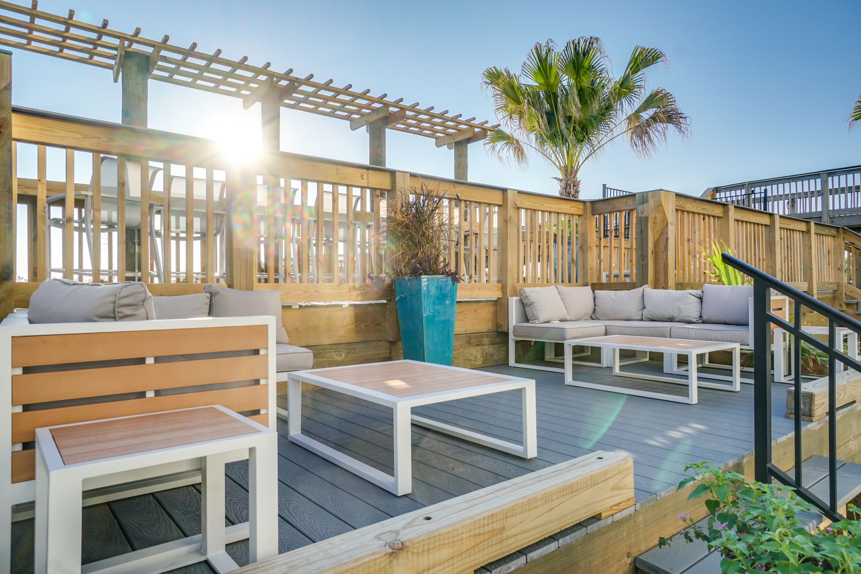 A wooden deck with outdoor seating, including a sofa and chairs, and a small table.