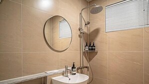 Une salle de bain moderne avec un grand miroir rond, un lavabo, des toilettes et une douche.