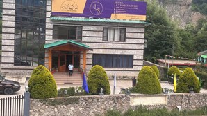 A hotel with a stone facade, a green roof, and a signboard advertising the hotel and restaurant. - Luxe Signature  (Manali)