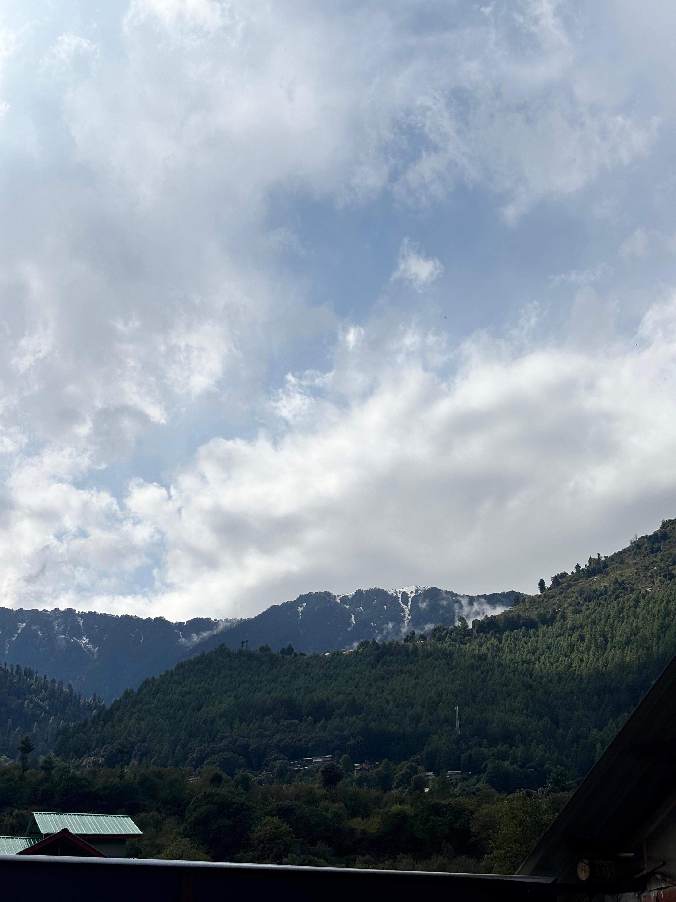 A mountainous landscape with a view of a valley and a building with a green roof.