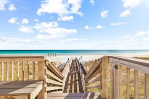 A wooden boardwalk leading to a beach with clear skies.