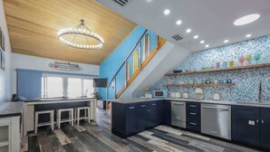 Eine moderne Küche mit Holzboden, einer Treppe und einer blauen gefliesten Rückwand.