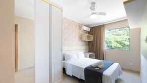 A bedroom with a bed, a ceiling fan, an air conditioning unit, a window with a view of greenery, and a sliding door. - Apt. w/ Balcony 500m From the Beach Rei0206 (Salvador)