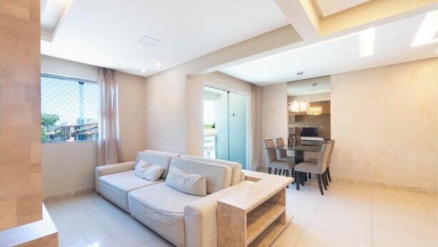 A modern living room with a sofa, a dining table with chairs, and a kitchen area visible through an open door. - Apt. w/ Balcony 500m From the Beach Rei0206 (Salvador)