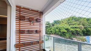 A balcony with a wooden slat wall, a glass railing, and a view of trees and a street. - Apt. w/ Balcony 500m From the Beach Rei0206 (Salvador)