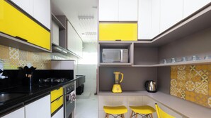 A compact kitchen with a gas stove, microwave, blender, and yellow chairs. - Apt. w/ Balcony 500m From the Beach Rei0206 (Salvador)