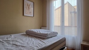 Een slaapkamer met een bed, een inlijsting foto aan de muur en een raam met gordijnen.