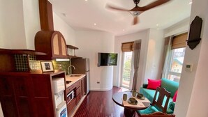 A modern kitchen with a built-in oven, a dining area with a round table and chairs, and a living room with a sofa and a television. - Tranquil Truc Bach (Hanoi)