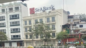 A view of a building with a SeA Bank sign, a water body in the foreground, and a white railing. - Tranquil Truc Bach (Hanoi)