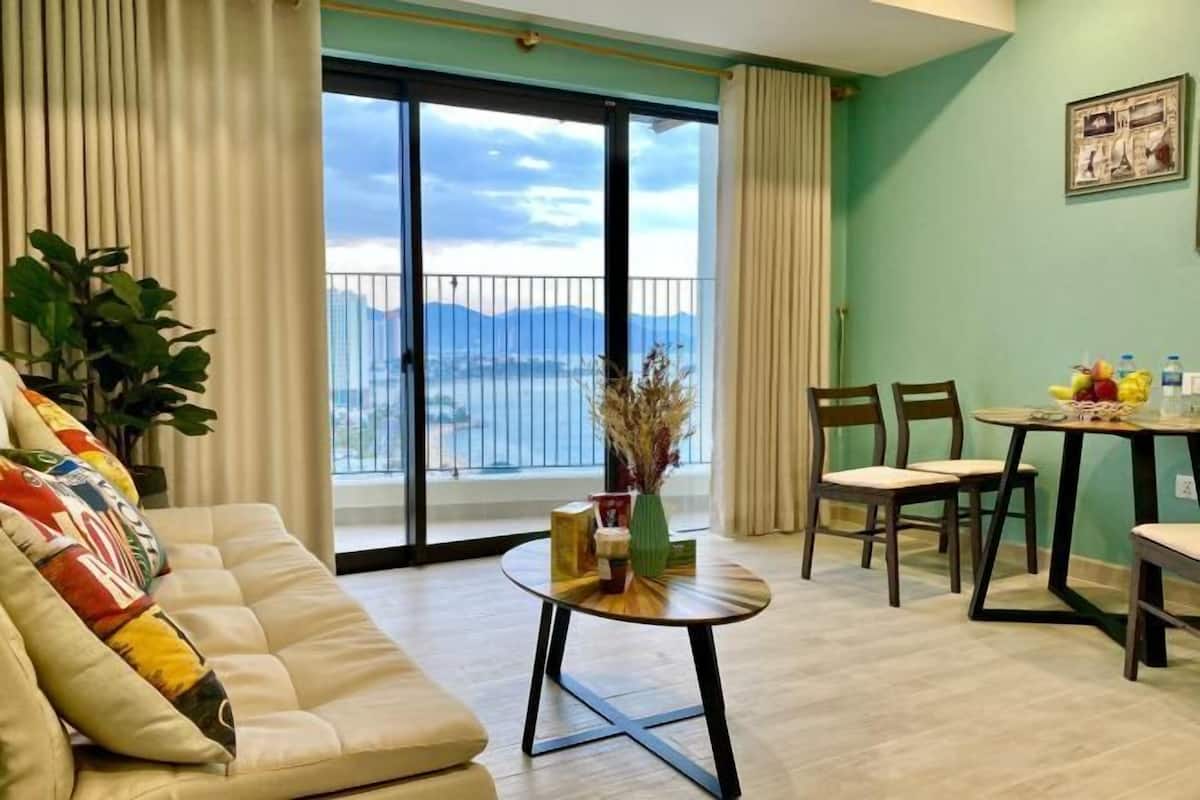 A living room with a sofa, chairs, a small table, and a view through a sliding door.