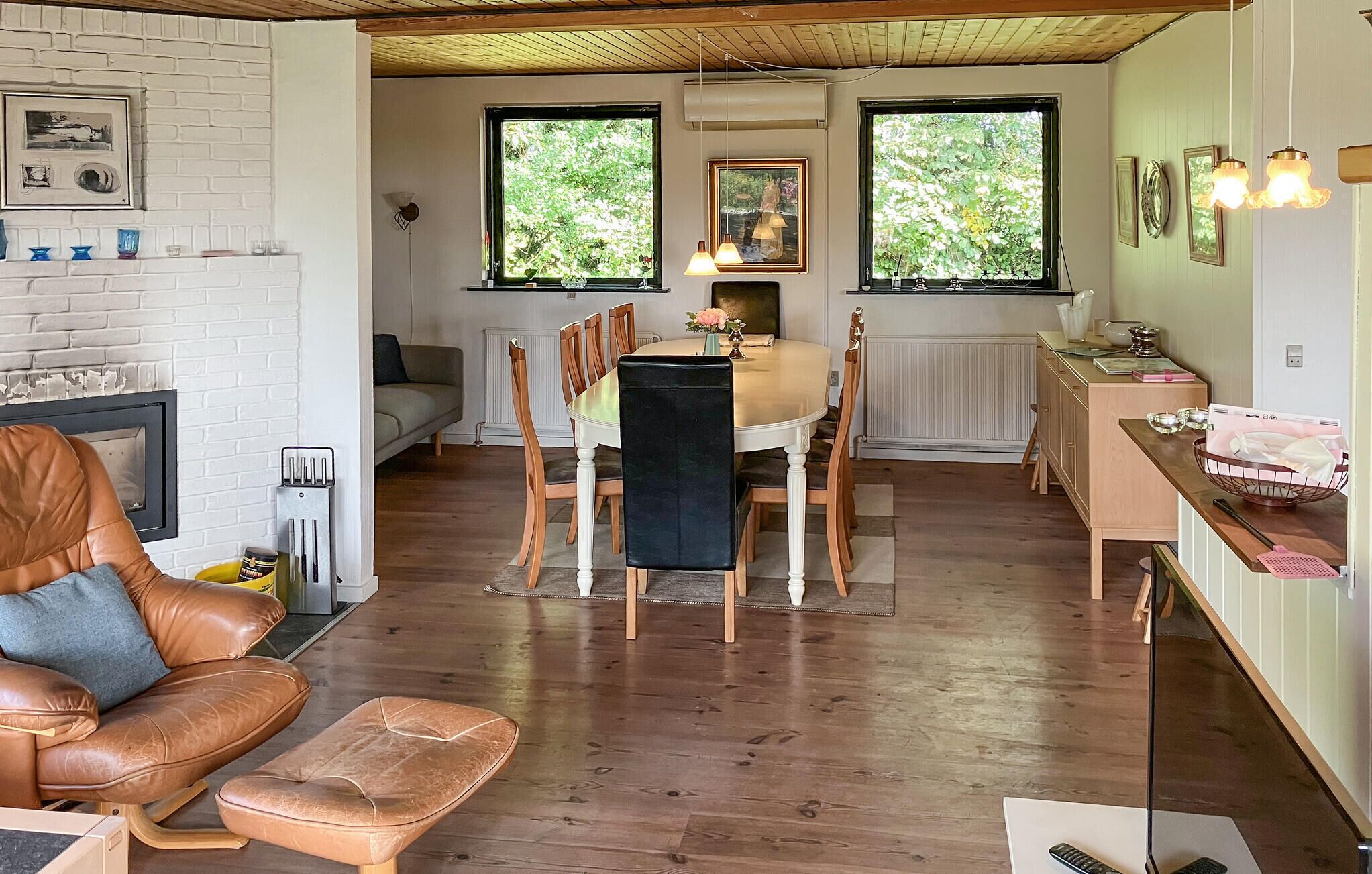 Una sala de estar acogedora con chimenea, un comedor con mesa y sillas, y una cocina con mostrador y armarios.