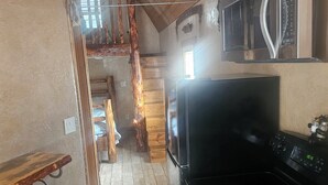 A kitchen with a black stove, wooden cabinets, and a microwave. - Charming cabin with WIFI and AC in delightful Show Low, Az
Minimum 2 night stay. (Show Low)