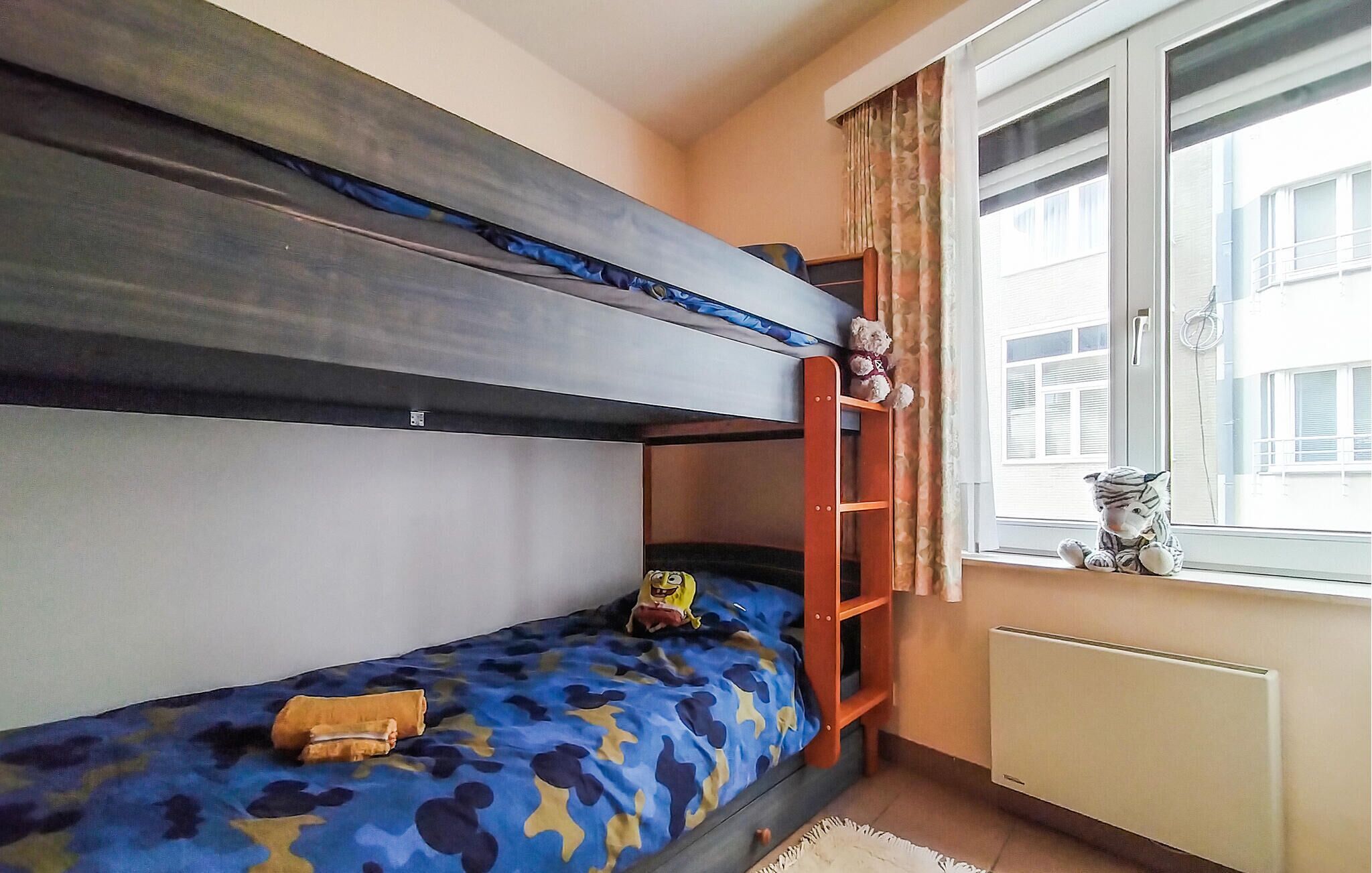 A bunk bed room with a window, a radiator, and a stuffed toy on the windowsill.