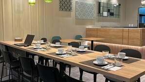 Un comedor moderno con una larga mesa de madera, sillas negras y lámparas colgantes verdes.