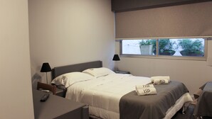 Una habitación de hotel con cama, mesitas de noche, un escritorio y ventana con vistas a zonas verdes.