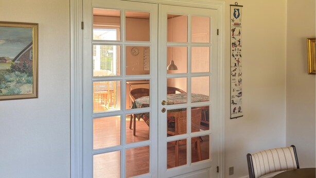 A room with a white door leading to a dining area, a wall-mounted tapestry, and a framed painting. - 3 bedroom gorgeous home in Ulfborg (Ulfborg)