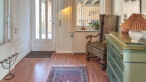 A room with a wooden floor, a patterned rug, a green dresser, a chair, a candelabra, and a door with a window. - 3 bedroom gorgeous home in Ulfborg (Ulfborg)