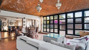 A spacious living area with a high ceiling, a large window with a view of the outside, and a seating area with a sofa and chairs. - Quinta Tere Country House (Zapopan)