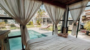 A room with a bed, a view of a swimming pool, and a fountain outside. - Quinta Tere Country House (Zapopan)