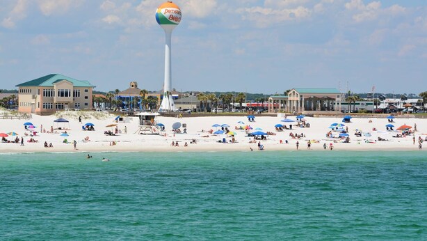 A beach with a water tower, beach umbrellas, and a lifeguard tower. - Pet Friendly East Hill New Build - Walk to Graffiti Bridge - Close to Downtown and Pensacola Beach (Pensacola)