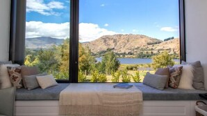 Una habitación con un ventanal que ofrece vistas a un lago y montañas.