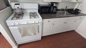 Una cocina con estufa blanca, hervidor, microondas y cafetera.