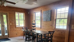 A wooden interior with a dining table and chairs, large windows, and a ceiling fan. -  Farmhouse close to wedding venues, hunting plantations in Whigham - 3 bedrooms (Whigham)