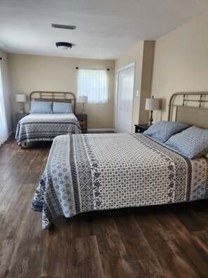 A bedroom with two beds, wooden flooring, and a window with curtains. - Farmhouse close to wedding venues, hunting plantations in Whigham - 3 bedrooms (Whigham)