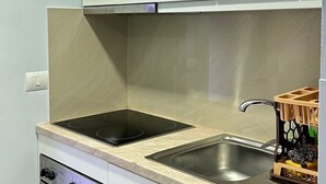 Cozinha com armários brancos, pia dupla, fogão e lava-louças.