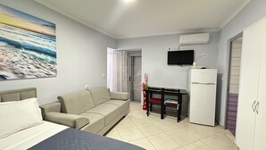 Quarto com cama, sofá, televisão e frigorífico.