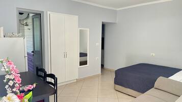 A bedroom with a bed, a desk with a chair, a wardrobe, and a bathroom with a shower.